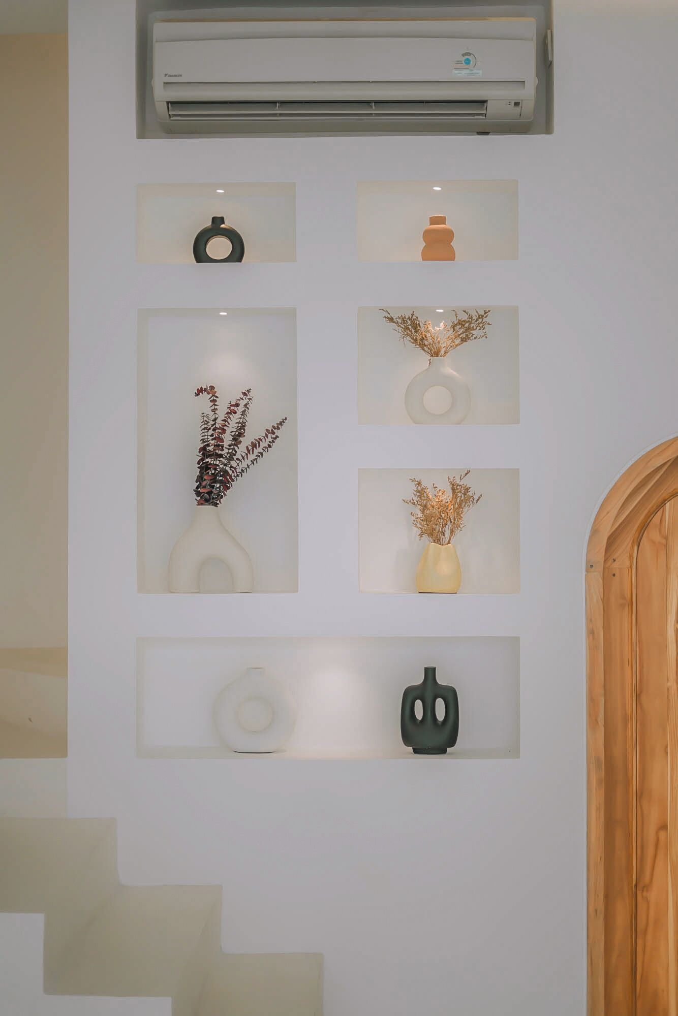 A wall with a series of framed artworks and a central air conditioning unit.