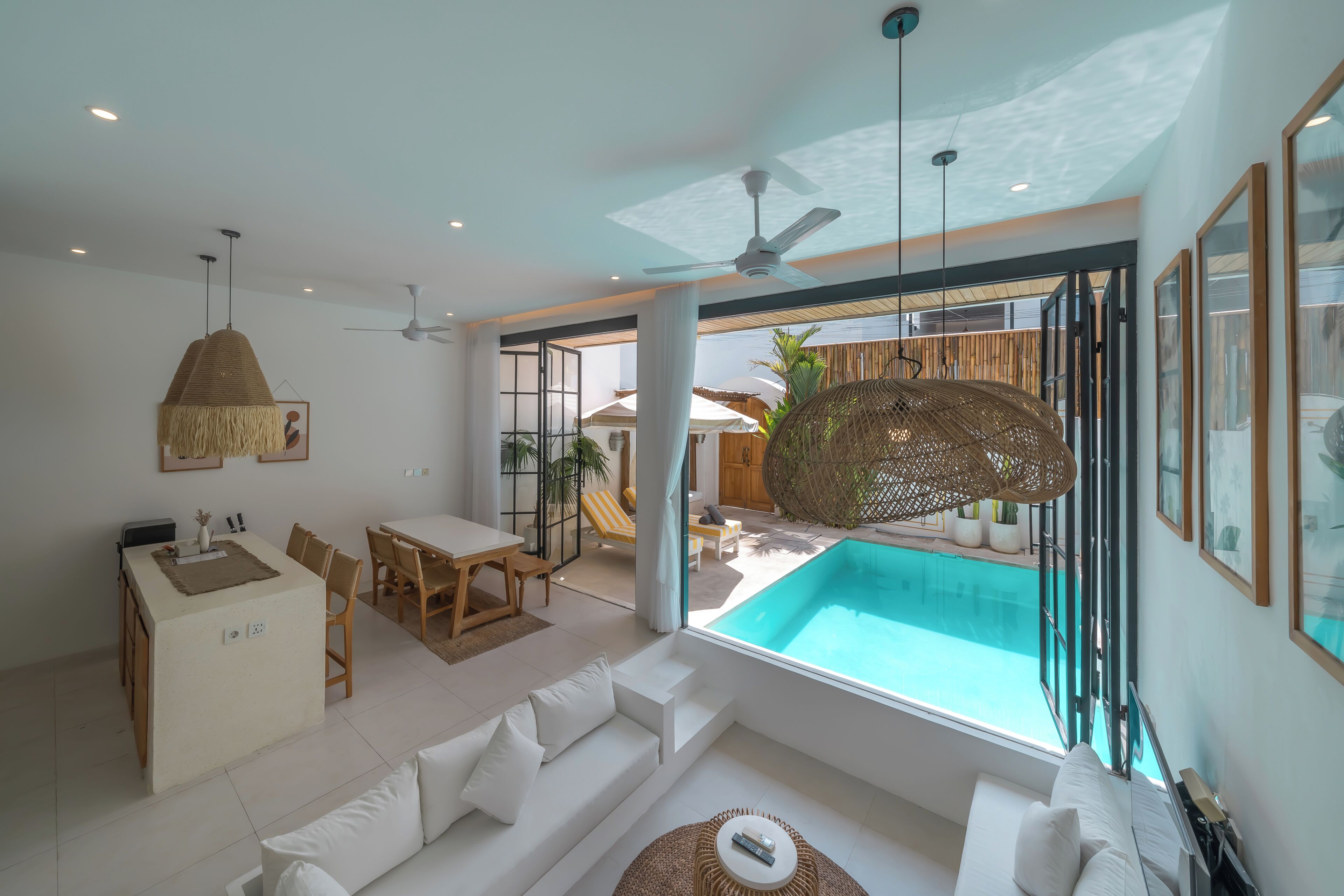 A modern living room with a pool view, a dining area, and a ceiling fan.
