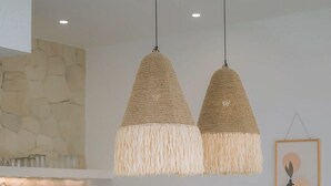 Une cuisine moderne avec un îlot central, des chaises en bois et des luminaires suspendus.