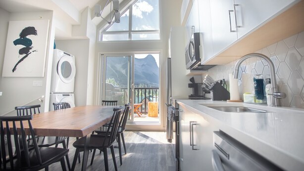 Een moderne keuken met een eethoek, grote ramen en uitzicht op bergen.