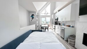 Een moderne, compacte leefruimte met een bed, kitchenette en eethoek.