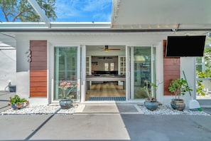 A modern house with a sliding glass door entrance, a ceiling fan, and a flat-screen TV mounted on the wall.