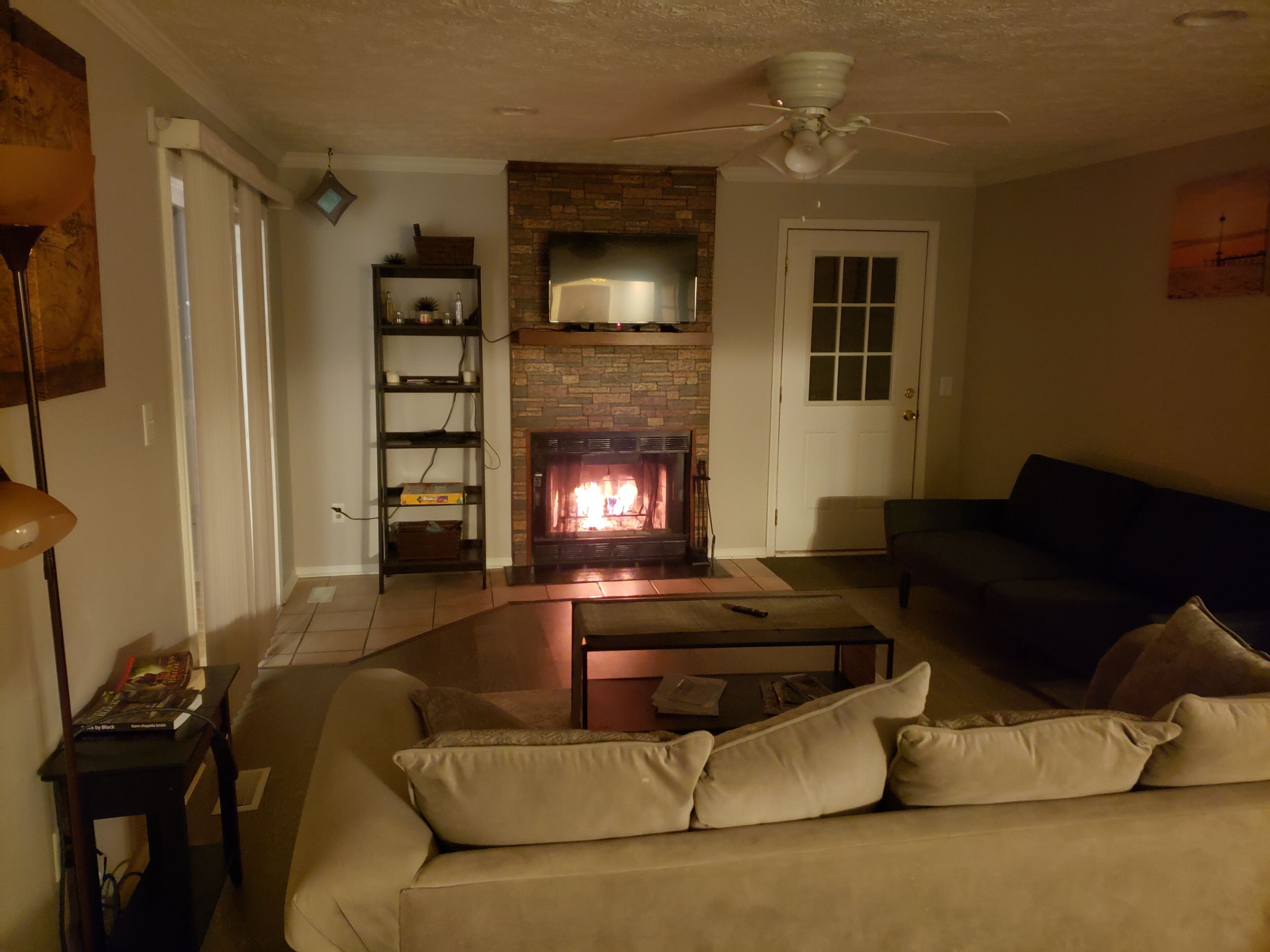 A living room with a fireplace, a sofa, a coffee table, and a bookshelf.