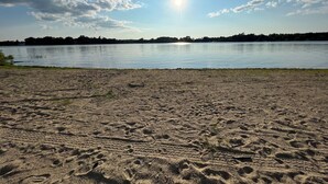 Une plage de sable où l’on peut voir des empreintes de pas qui mènent à un lac paisible.