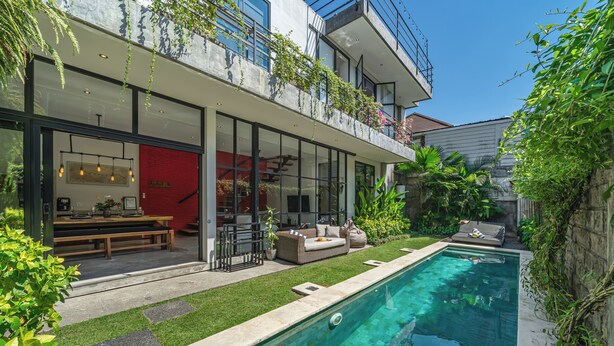 A modern house with a swimming pool, outdoor seating, and a red wall. - Villa Jungalow 2BR Pool Villa Near Beach Café del Mar & Padel (Canggu)