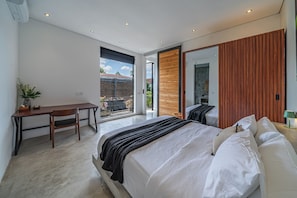 Ein Schlafzimmer mit Bett, Schreibtisch und einer Schiebetür, die auf einen Balkon führt.