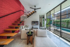 A modern interior with a staircase, a sofa, a coffee table, and a view of a swimming pool. - Villa Jungalow 2BR Pool Villa Near Beach Café del Mar & Padel (Canggu)