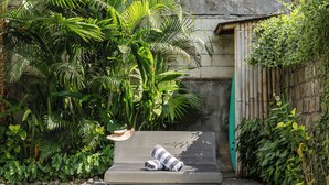 A swimming pool with a lounge chair and a surfboard, surrounded by lush greenery. - Villa Jungalow 2BR Pool Villa Near Beach Café del Mar & Padel (Canggu)