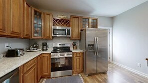 A kitchen with wooden cabinets, stainless steel appliances, a microwave, a coffee maker, and a refrigerator.