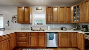 A kitchen with wooden cabinets, a stainless steel dishwasher, and a granite countertop.