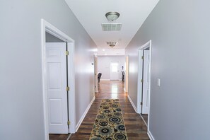 Un couloir avec des portes blanches, une moquette à motifs et un luminaire au plafond.