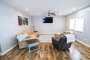 Relax in this inviting living room with a large flat-screen TV, comfortable seating areas, and a cozy coffee table.