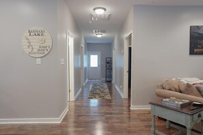 Stylish hallway leading to a door, featuring a decorative wall sign and a cozy seating area.