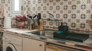 Une cuisine équipée d’un lave-linge, d’un évier et de divers ustensiles de cuisine.