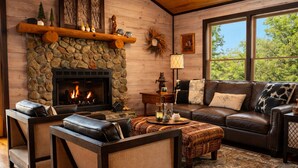 A cozy living room with a stone fireplace, leather furniture, and a large window.