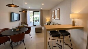 A modern living room with a dining area, a sofa, a TV, and a bar with stools.