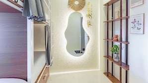 Habitación de hotel con un espejo grande, una estantería de madera con adornos, y una señal colgada en la pared.