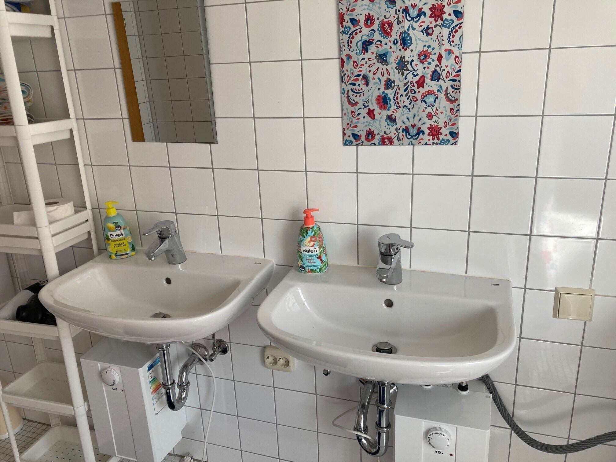 A bathroom with two sinks, a mirror, and a decorative tile wall.