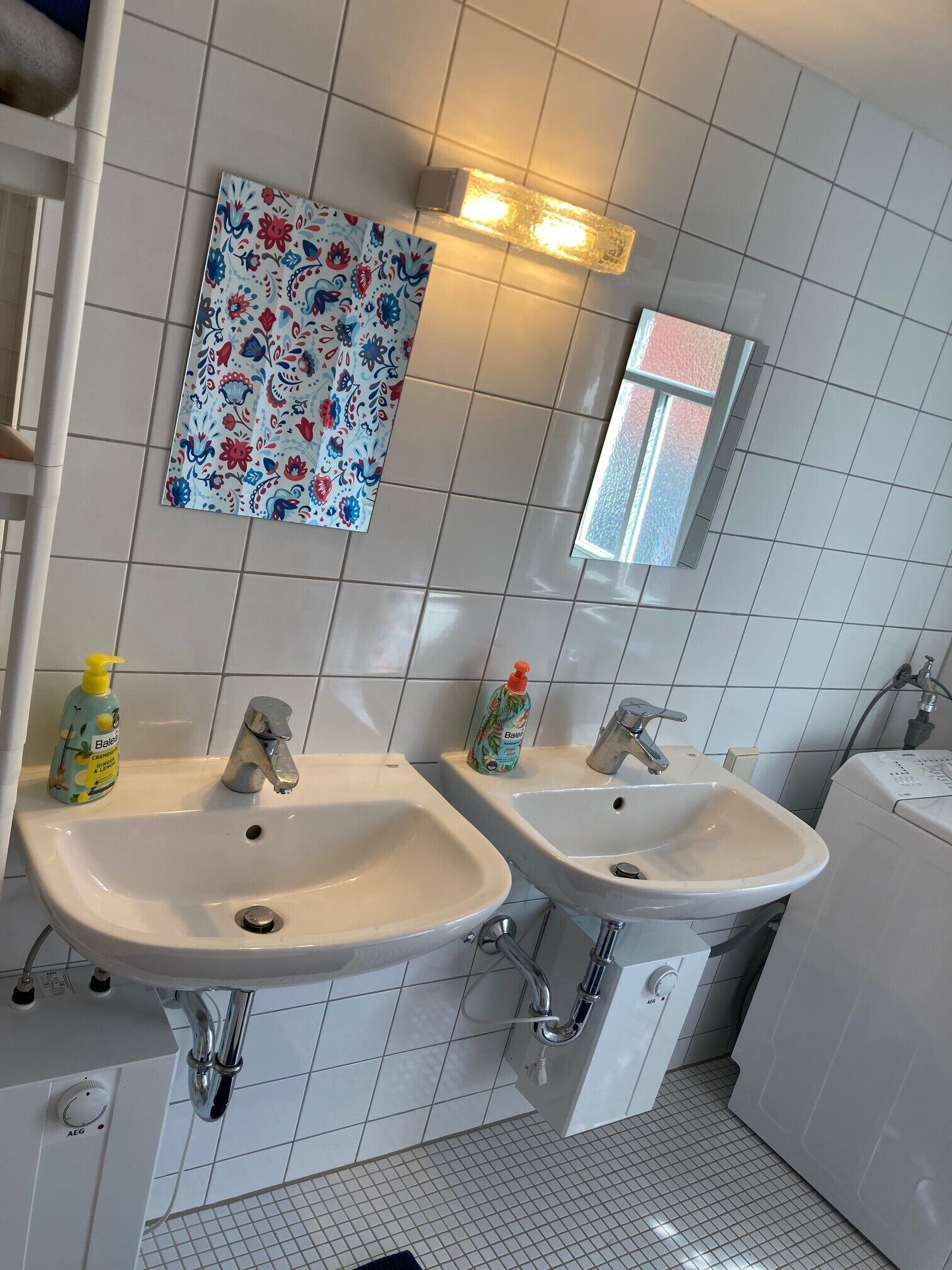 Un baño con dos lavamanos, un espejo y una lámpara empotrada en la pared.