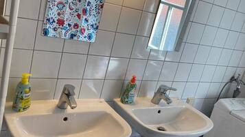Un baño con dos lavamanos, un espejo y una lámpara empotrada en la pared.