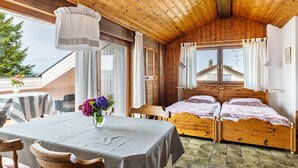 Eine Holzhütte mit einem Bett, einem Esstisch mit Stühlen und einem Fenster mit Vorhängen.