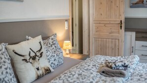 A bedroom with a bed, pillows, a lamp, and a wooden door. - Apartment 'Harzperle Nr 6' with Mountain View, Balcony and Wi-Fi (Braunlage)