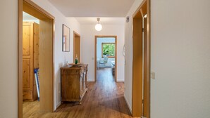 Un couloir doté d’un plancher en bois, d’une armoire en bois et d’une porte donnant sur une pièce avec une fenêtre.
