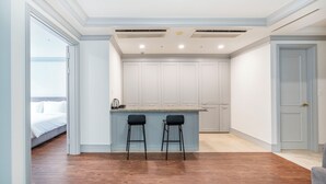 A modern kitchen with white cabinets, two bar stools, and a breakfast bar. - Centum Converntion Hotel (Busan)