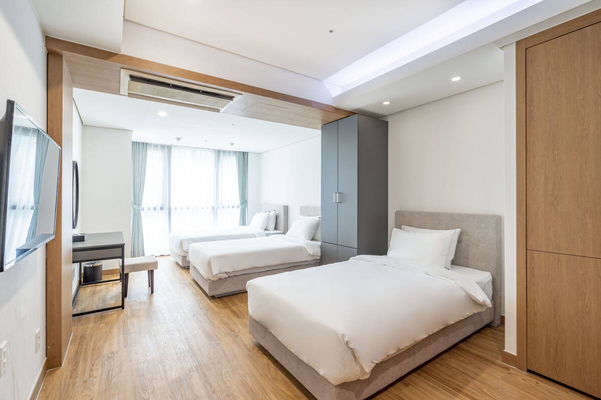 Una habitación de hotel moderna con dos camas, un escritorio y un televisor.