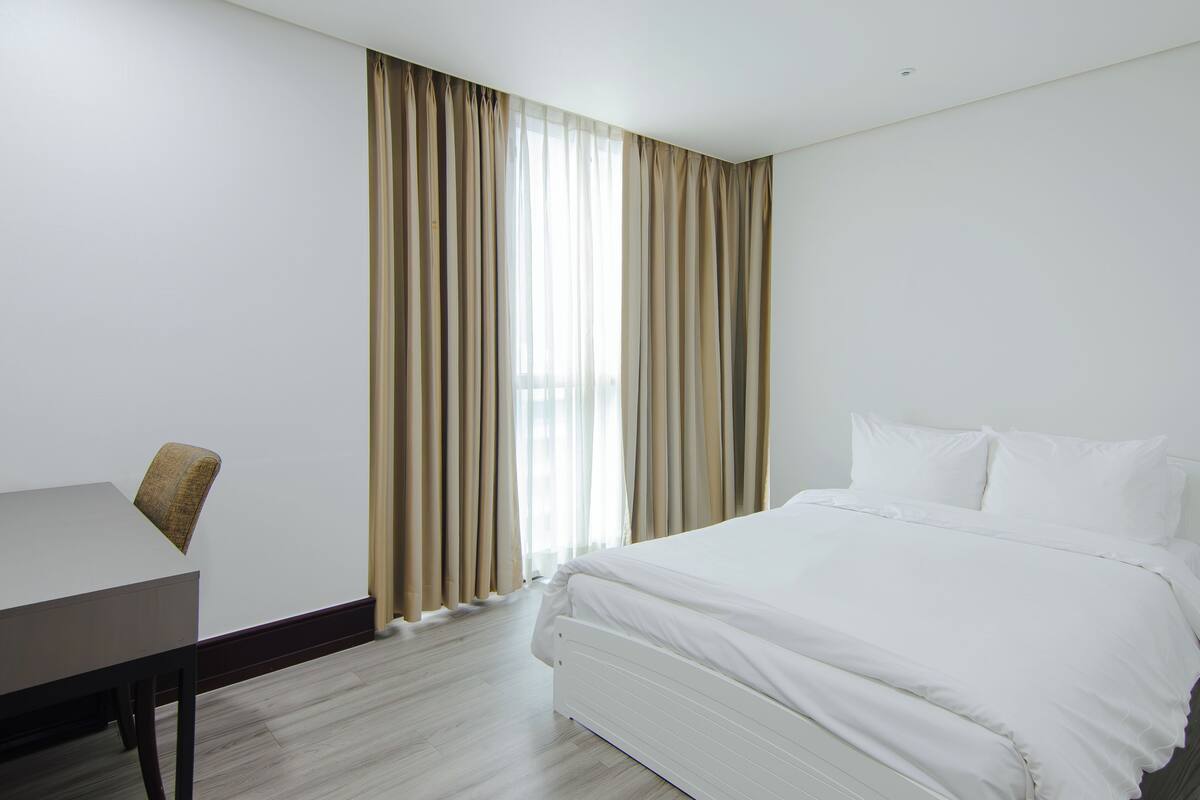 Una habitación de hotel con cama, escritorio y cortinas.