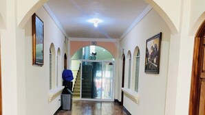 A hallway with a checkered floor, arched ceilings, and framed pictures on the walls. - Hotel del Carmen (San Felipe)