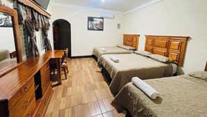 A hotel room with two beds, a wooden dresser, a desk, a chair, a television on the wall, and a painting on the wall. - Hotel del Carmen (San Felipe)