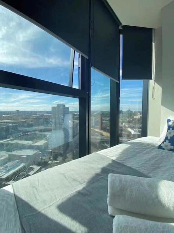 Enjoy a panoramic city view from the large window, with a comfortable bed and flat-screen TV.