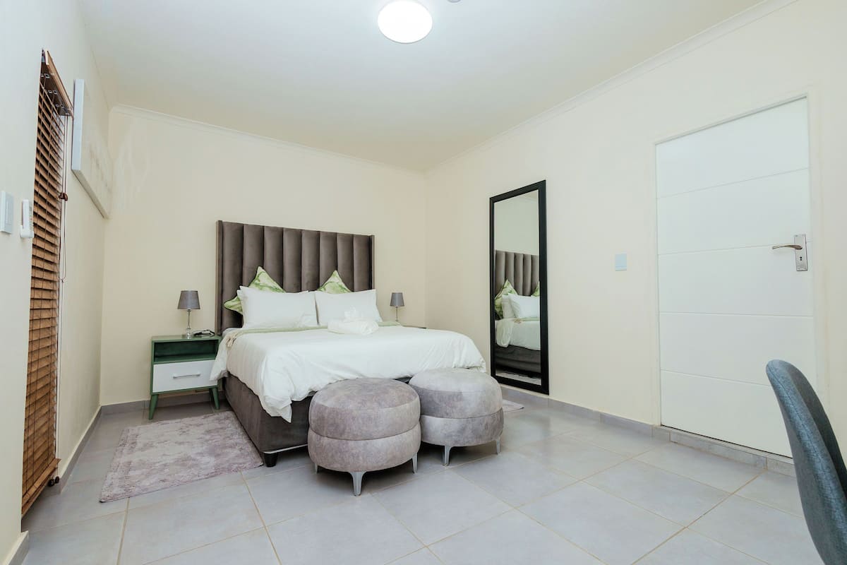 Un dormitorio con cama, mesitas de noche, un espejo y una puerta.