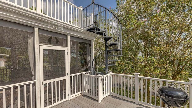 Eine Terrasse mit weißer Geländer, einer Wendeltreppe und einem Grill.