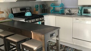 A kitchen with white cabinets, a stove, a microwave, a toaster, and a sink. - The Haven’s hideaway (Freeport)