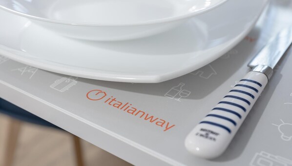 A kitchen counter with a white plate and a knife with a striped handle. The word "italianway" is visible on the counter.