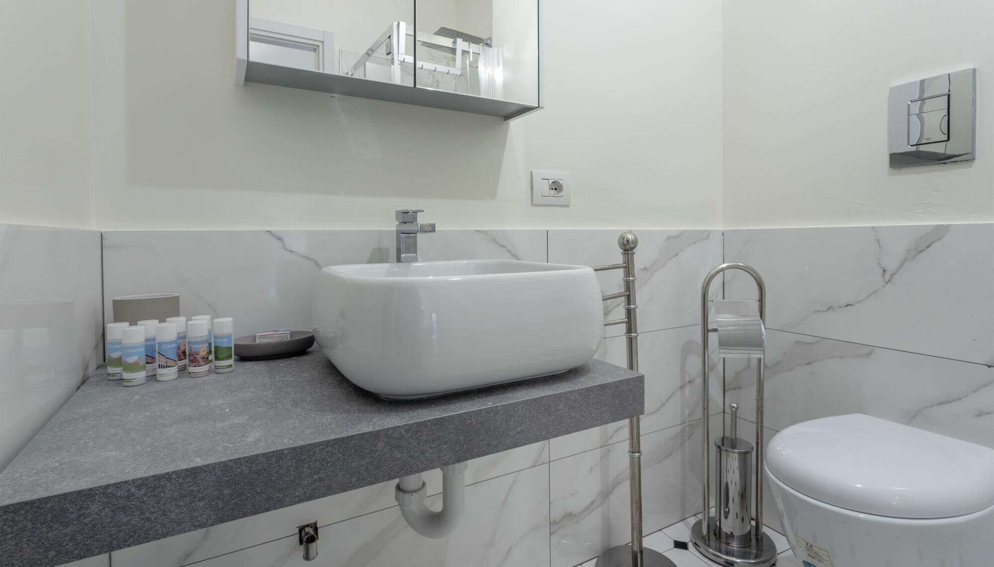 A modern bathroom with a white sink, a toilet, and a shower.
