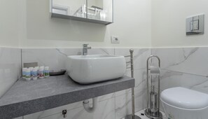 A modern bathroom with a white sink, a toilet, and a shower.