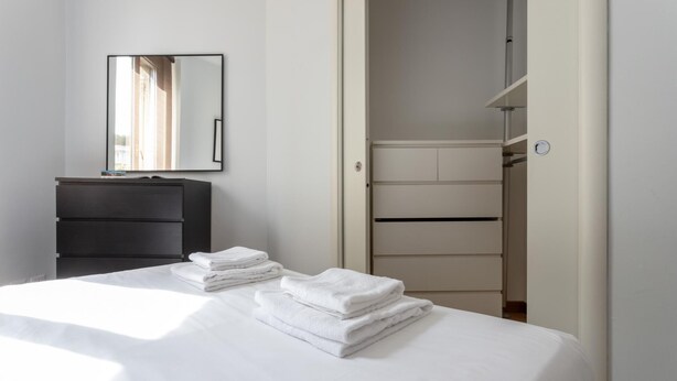 A hotel room with a bed, a dresser, a mirror, and a wardrobe. - Italianway Easy - Abruzzi 19 (Milan)