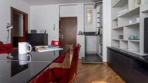 A modern kitchen with a black countertop, red chairs, and a white coffee machine. - Italianway Easy - Abruzzi 19 (Milan)