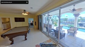 Une vaste salle de divertissement avec vue sur la piscine, un billard et un ventilateur de plafond.