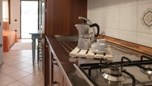 A kitchen with a gas stove, a coffee maker, and a sink. - Idyllic Residence Cala Viola Studio sleeps num1373 (Sos Alinos)