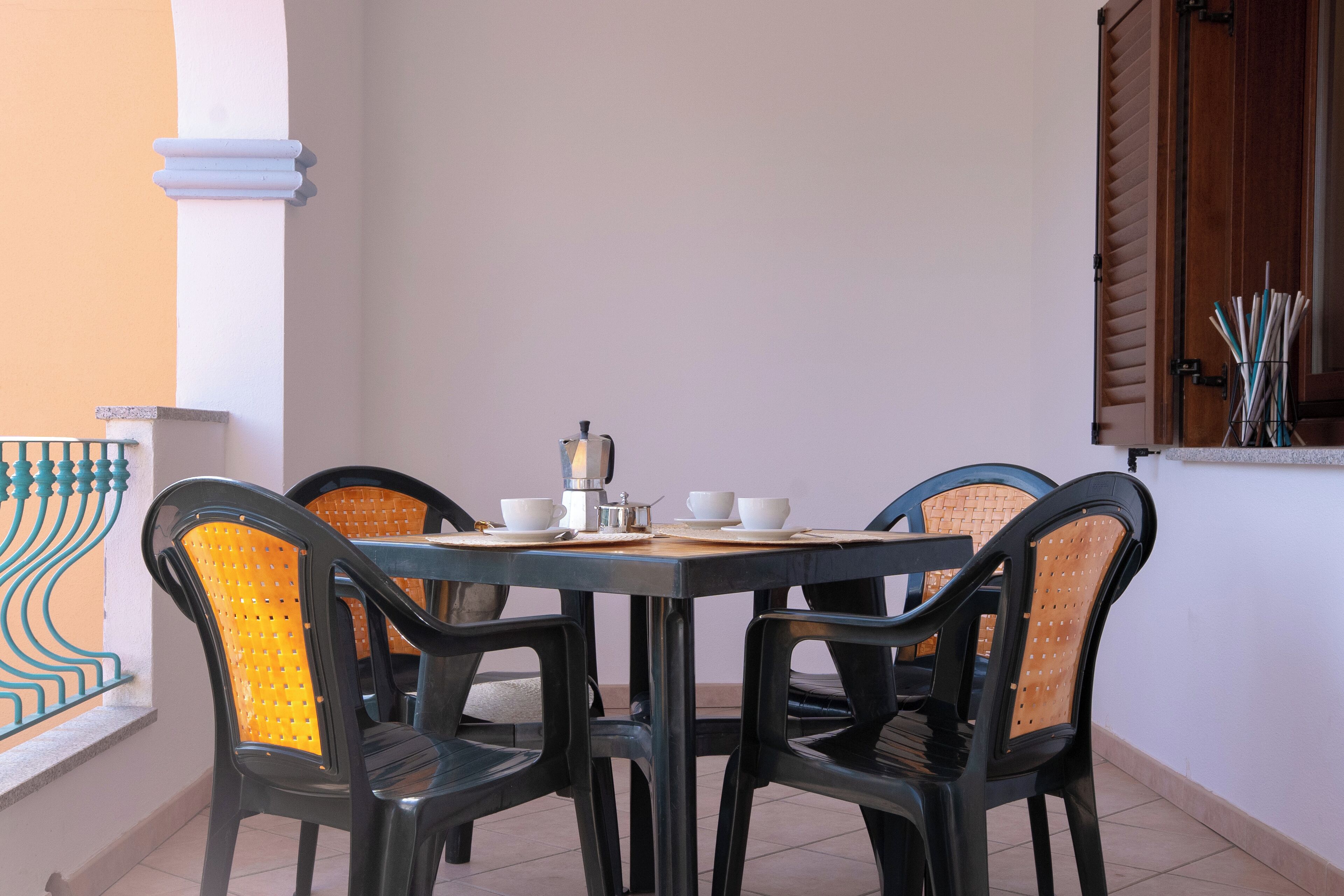 A dining area with a table and four chairs, a coffee maker, and a cup set.