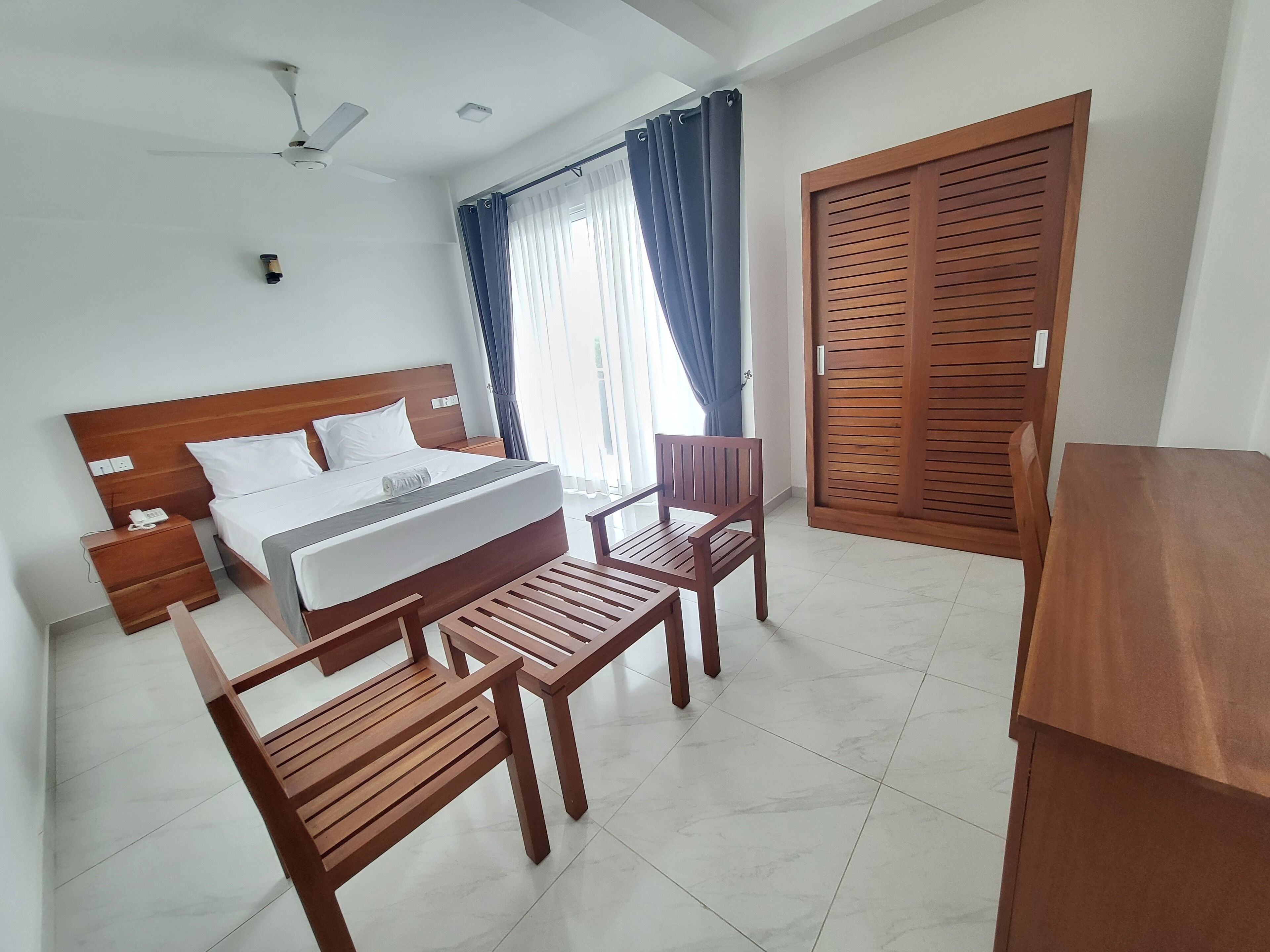 A hotel room with a wooden bed, a desk, a chair, and a wardrobe.