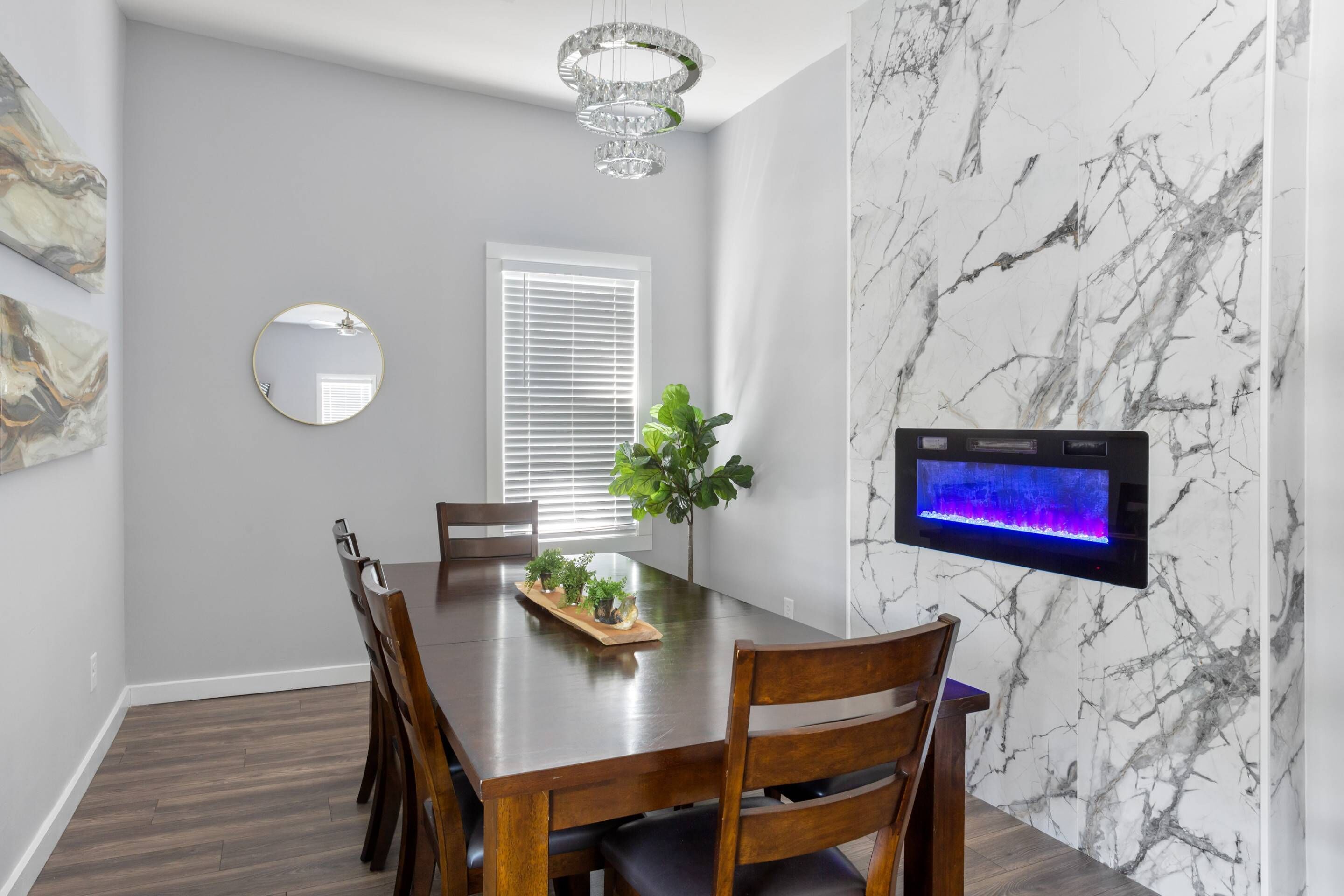 A dining area with a marble wall, a flat-screen TV, and a chandelier.