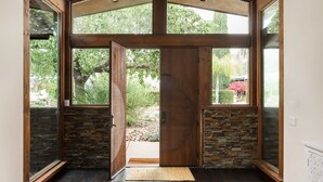 A spacious entryway with a wooden ceiling, large windows, and a stone accent wall. - Resort-Style 5 BR Retreat in Lake Hodges W Pool, Jacuzzi, Grill, Volleyball Court (Escondido)