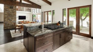 A modern kitchen with dark cabinetry, a granite countertop, and a built-in stove. - Resort-Style 5 BR Retreat in Lake Hodges W Pool, Jacuzzi, Grill, Volleyball Court (Escondido)