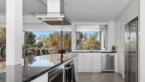 Una cucina moderna con un'isola grande, elettrodomestici in acciaio inossidabile e vista sugli alberi dalla finestra.