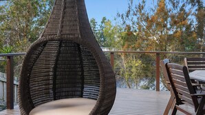 Una sedia in vimini con un cuscino su un pontile di legno.